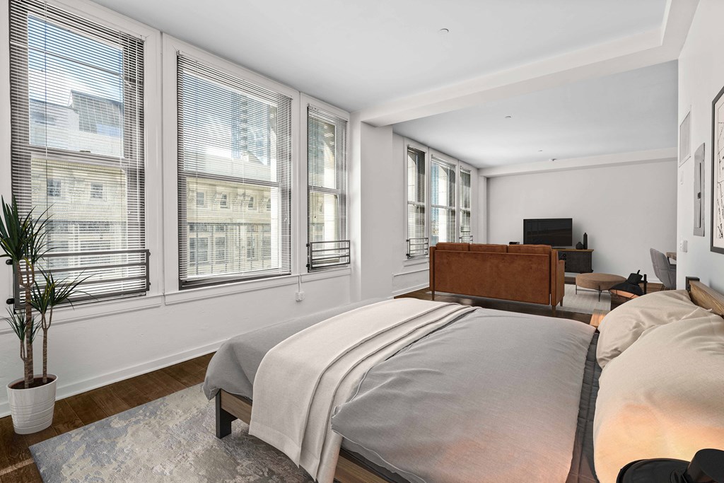 the master bedroom has a large bed and a large set of windows