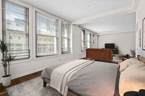the master bedroom has a large bed and a large set of windows
