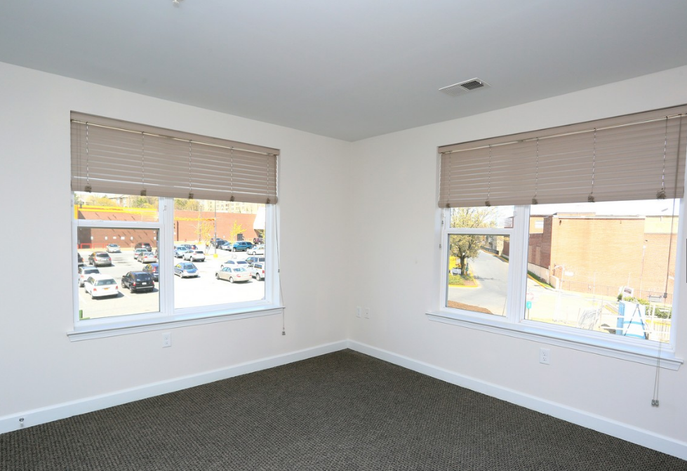 an empty room with two windows and a city street