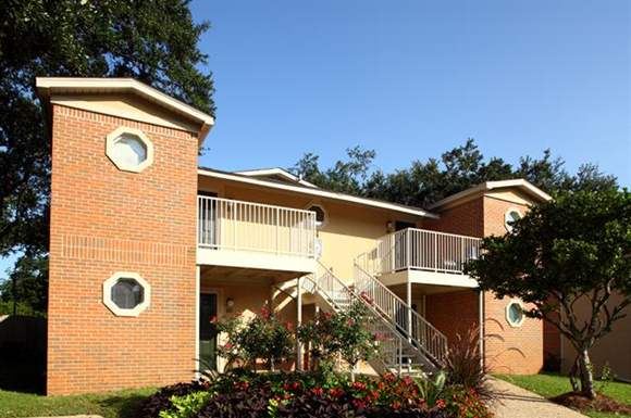 a building with a staircase and a tree in front of it
