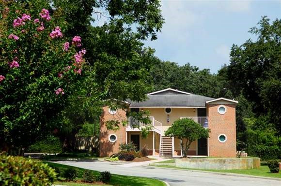 a red brick house with a tree with pink flowers
