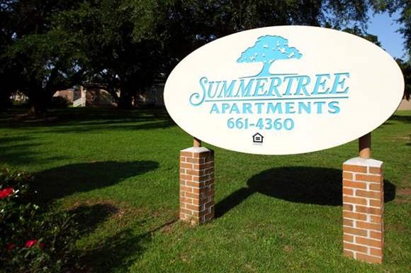a sign for thesummer tree apartments in the grass