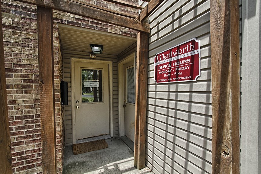 the front door of a brick building with a red and white sign at at Wentworth Estates Apartments, Florence, KY, 41042