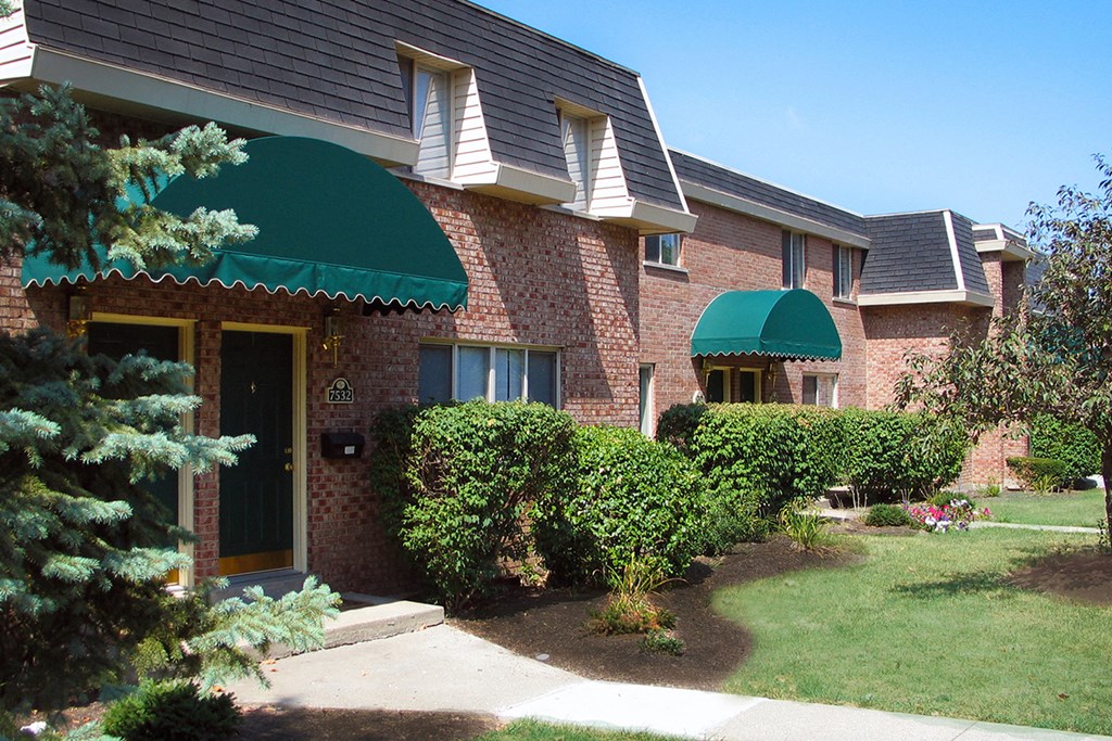 a brick house with a green awning and bushes in front of it at Wentworth Estates Apartments, Kentucky