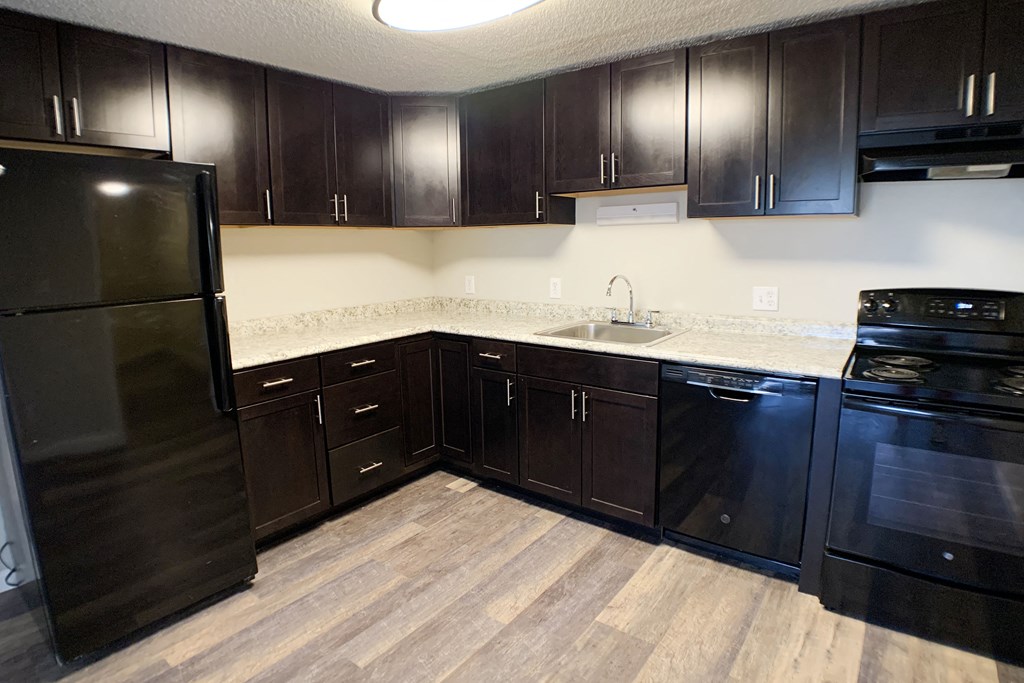 a kitchen with dark wood cabinets and a black refrigerator