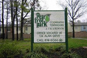 a sign in a grassy area with trees in the background