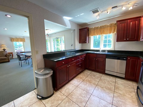 A kitchen with red cabinets and a stainless steel dishwasher.