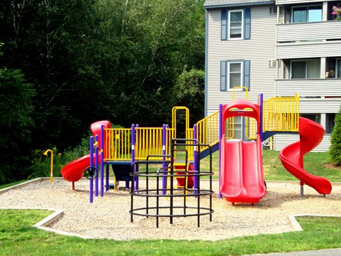 A playground with a red slide and a yellow and purple play structure.