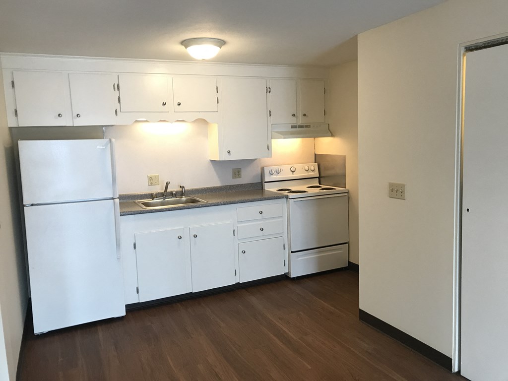 an empty kitchen with white appliances and white cabinets