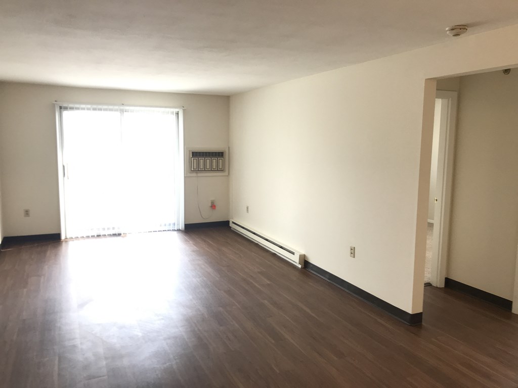 an empty living room with wood floors and a window