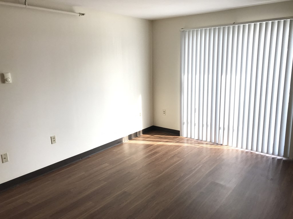 an empty living room with wood floors and a large window