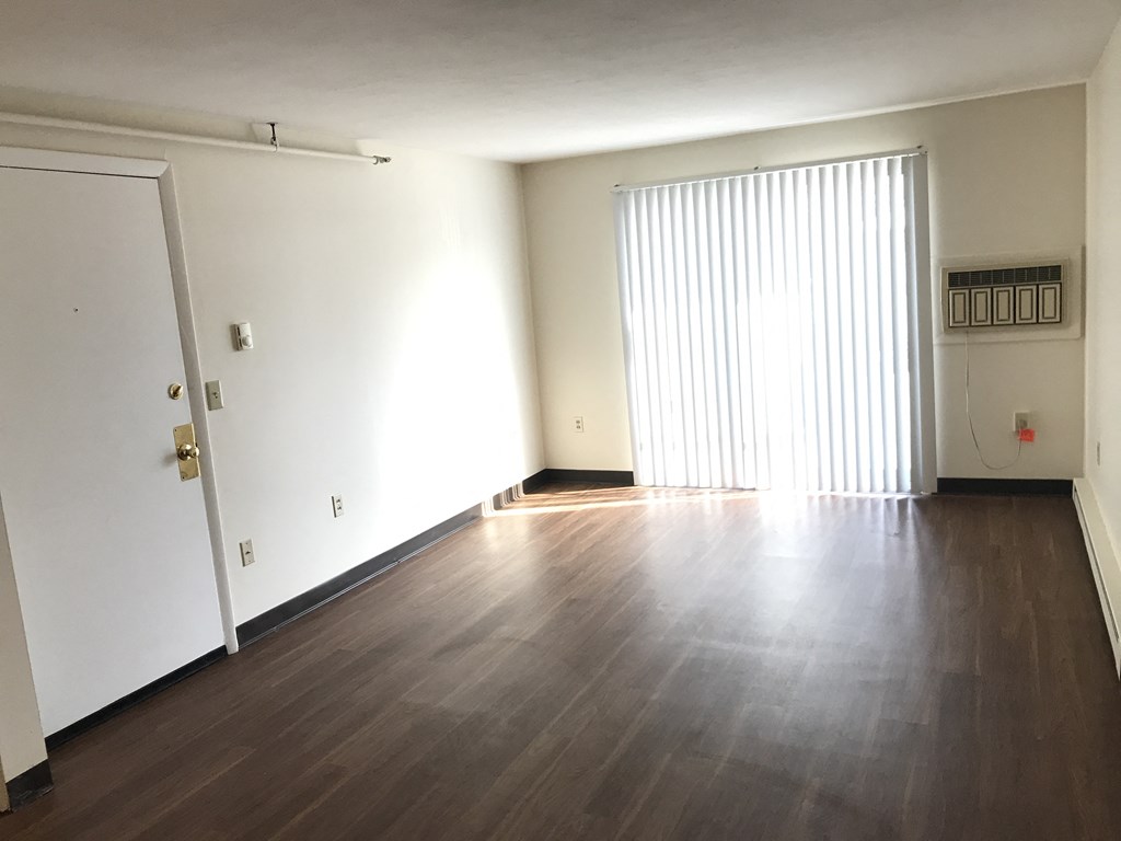 an empty living room with wood floors and a sliding glass door