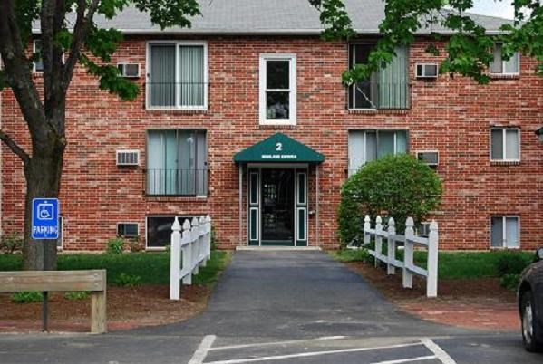 a red brick apartment building with a sidewalk in front of it