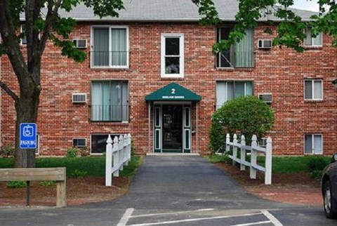 a red brick apartment building with a sidewalk in front of it
