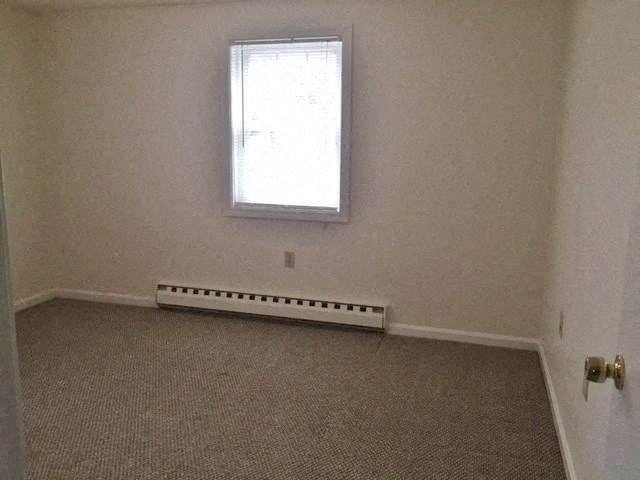 an empty room with a radiator and a window