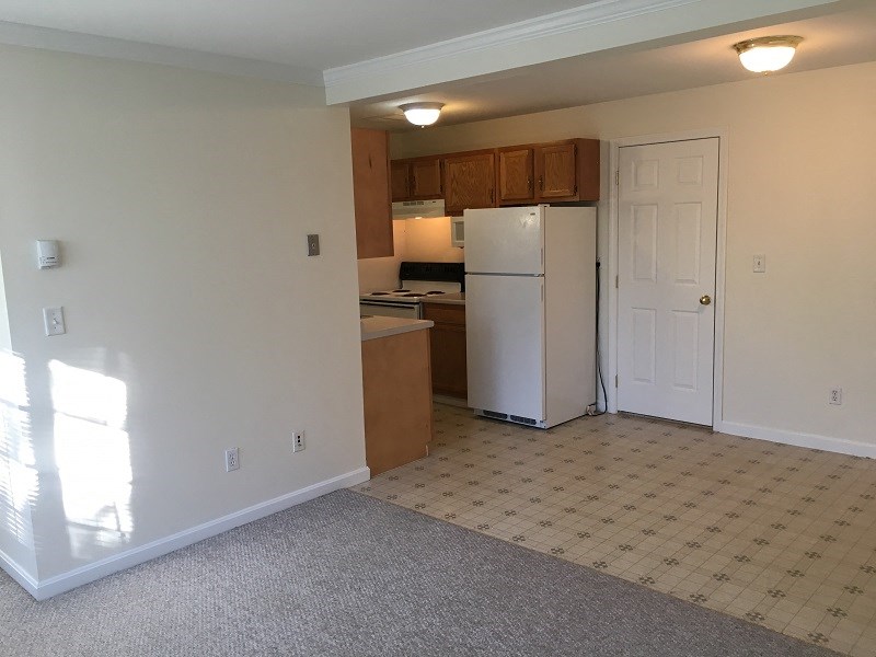 an empty kitchen with a refrigerator and a door
