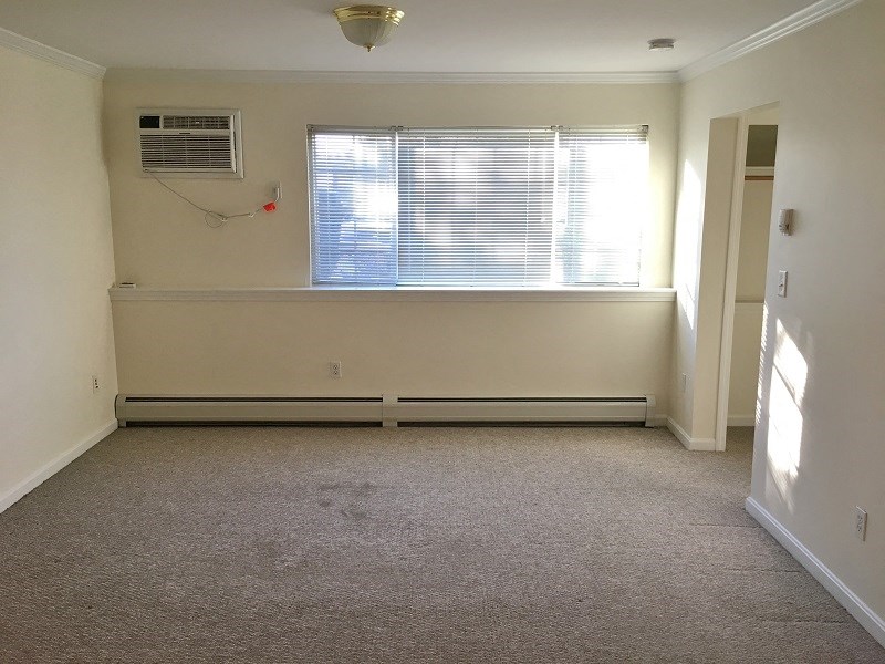 an empty room with a window and a air conditioner
