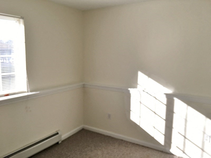 the corner of a room with white walls and a window