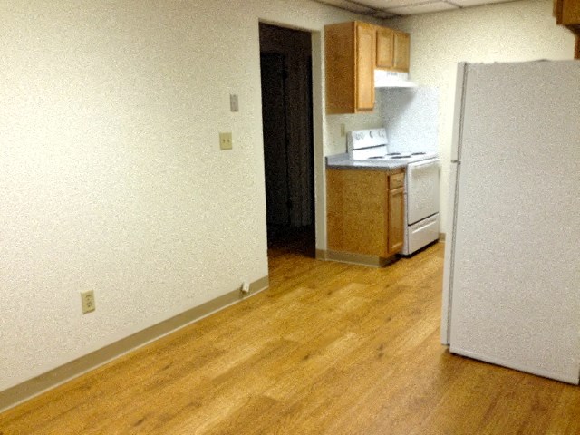 an empty room with a refrigerator and a kitchen