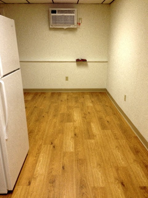 an empty room with wooden floors and a refrigerator