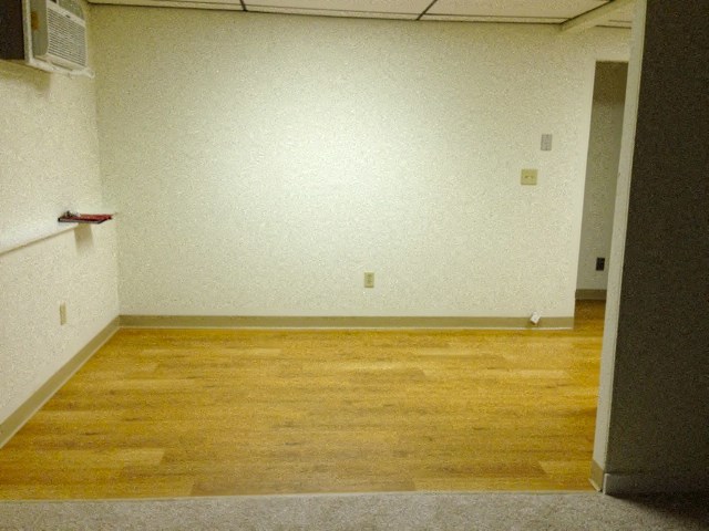 an empty room with wooden floors and a white wall