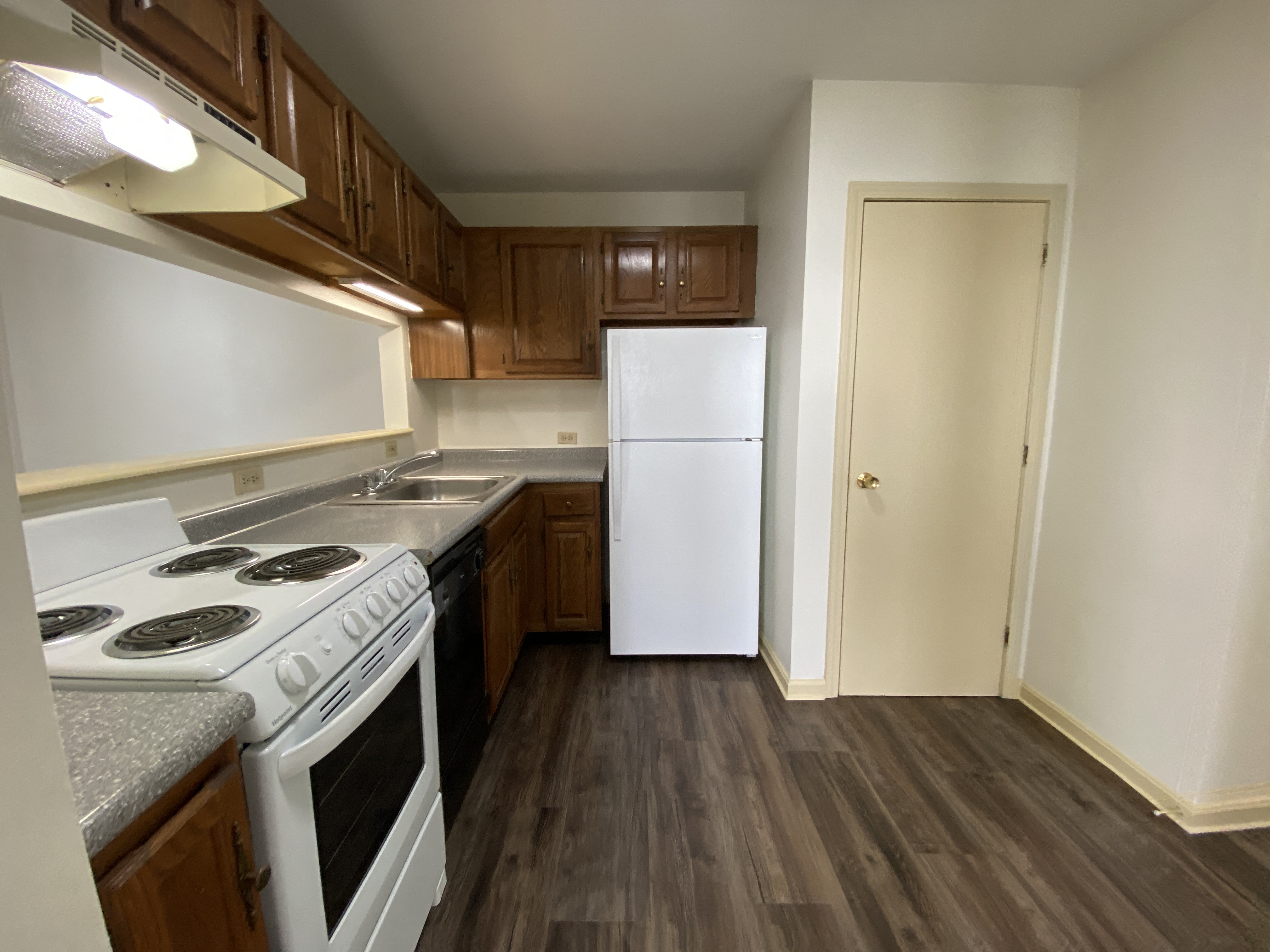 A kitchen with a white stove top oven and a white refrigerator.