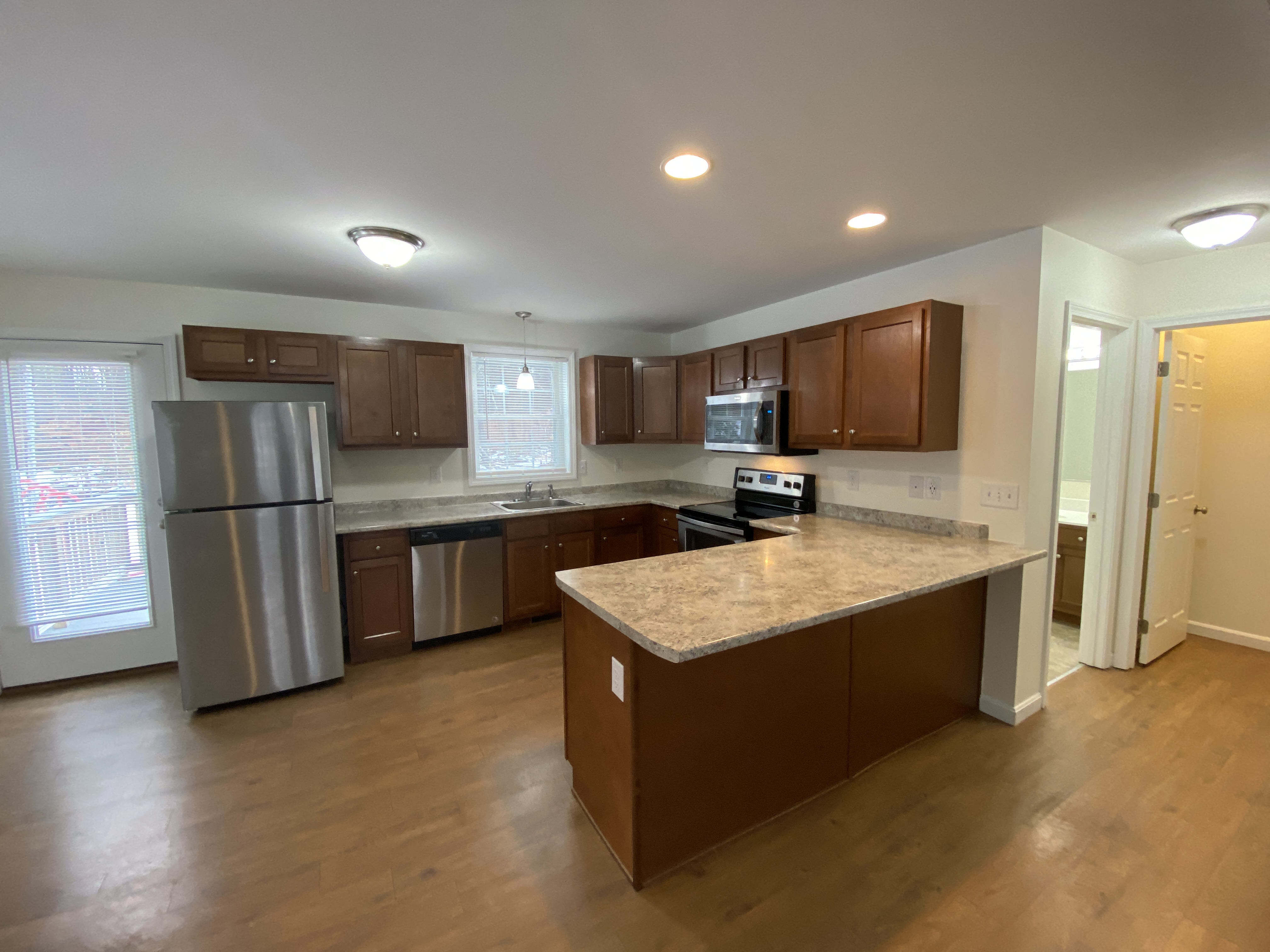 an empty kitchen with an island and stainless steel refrigerator