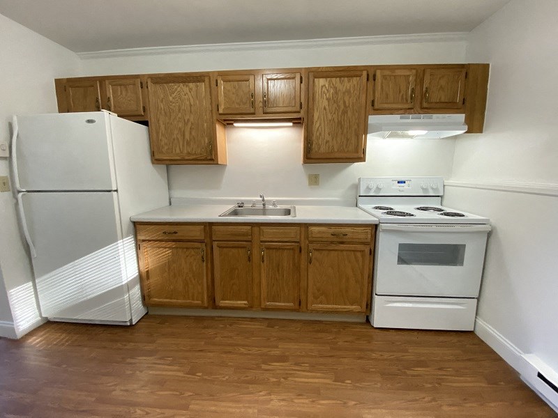 an empty kitchen with white appliances and wooden cabinets