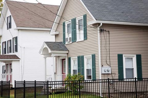 a white house with green windows and a black fence