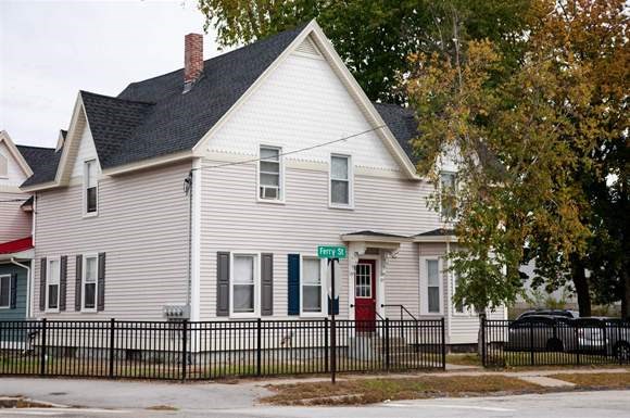 a white house with a black fence and a street sign