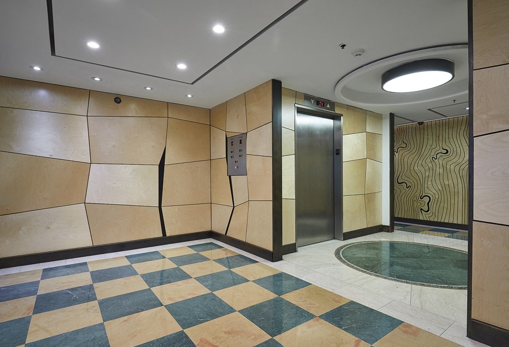 the elevator lobby of a building with a checkerboard floor and a glass door