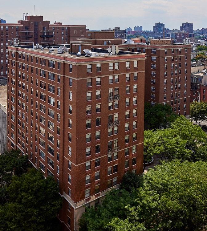 a view from above of a tall brick building with many windows and trees in front of it