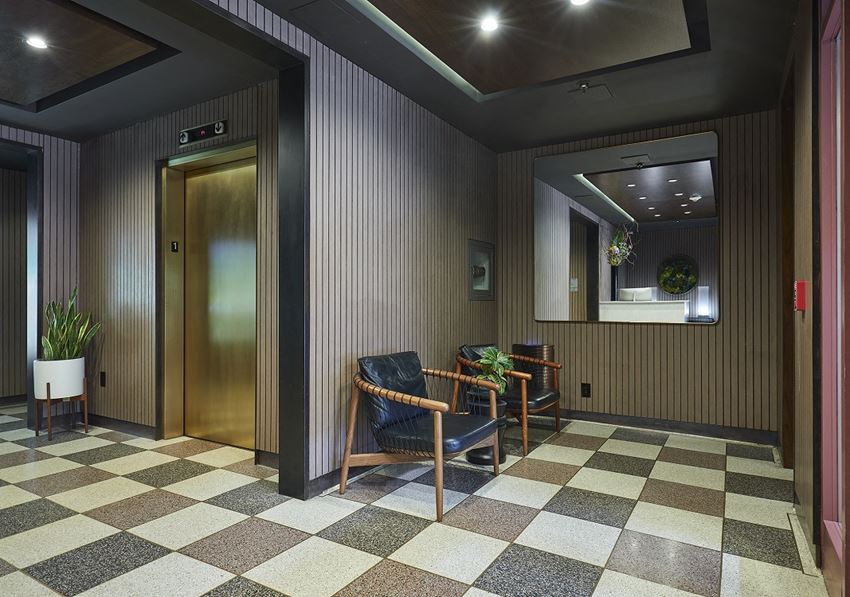 a dark room with a checkered floor and a bronze elevator