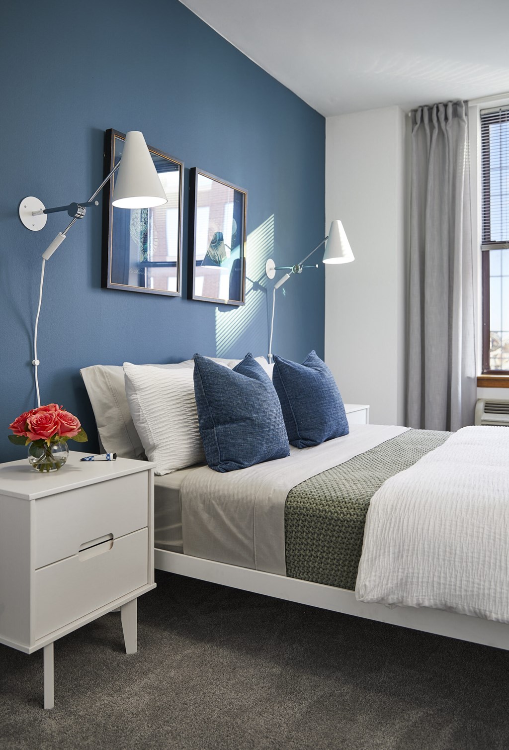 a blue and white bedroom with a bed and lamps