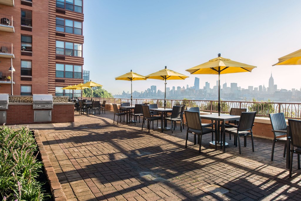 a rooftop patio with tables and umbrellas and a view of the city