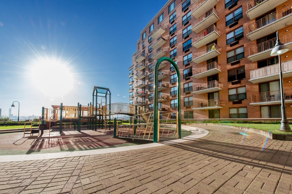 a playground in front of an apartment building with the sun shining
