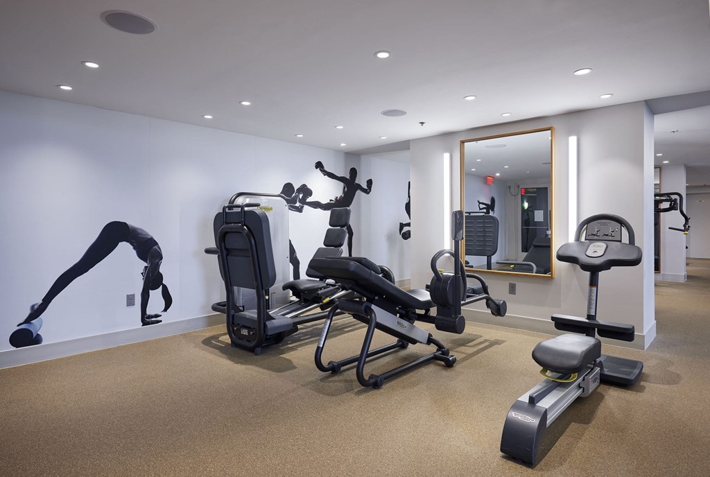 a gym with machines and weights in a room with a mirror