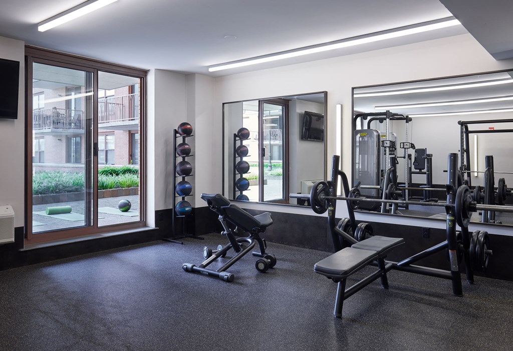 a gym with weights and mirrors and a window