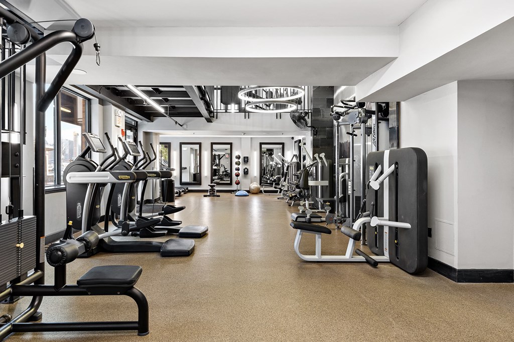 a gym with cardio equipment and weights on the floor