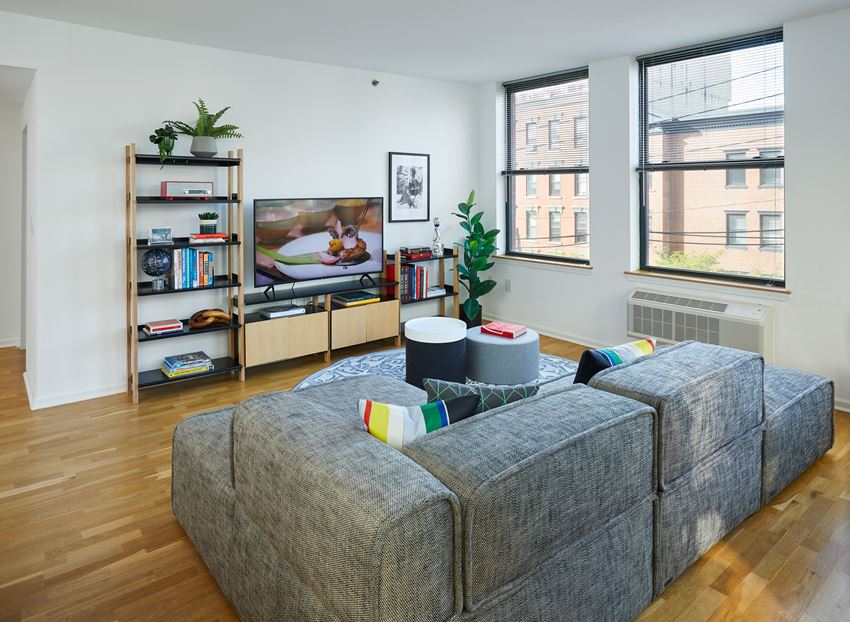 a living room with a gray couch and two windows