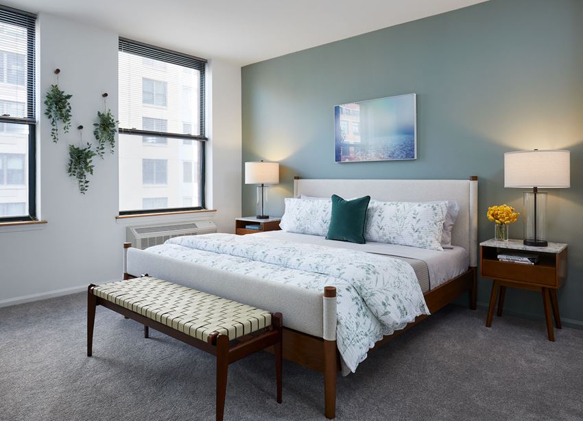 a bedroom with a large bed and two windows