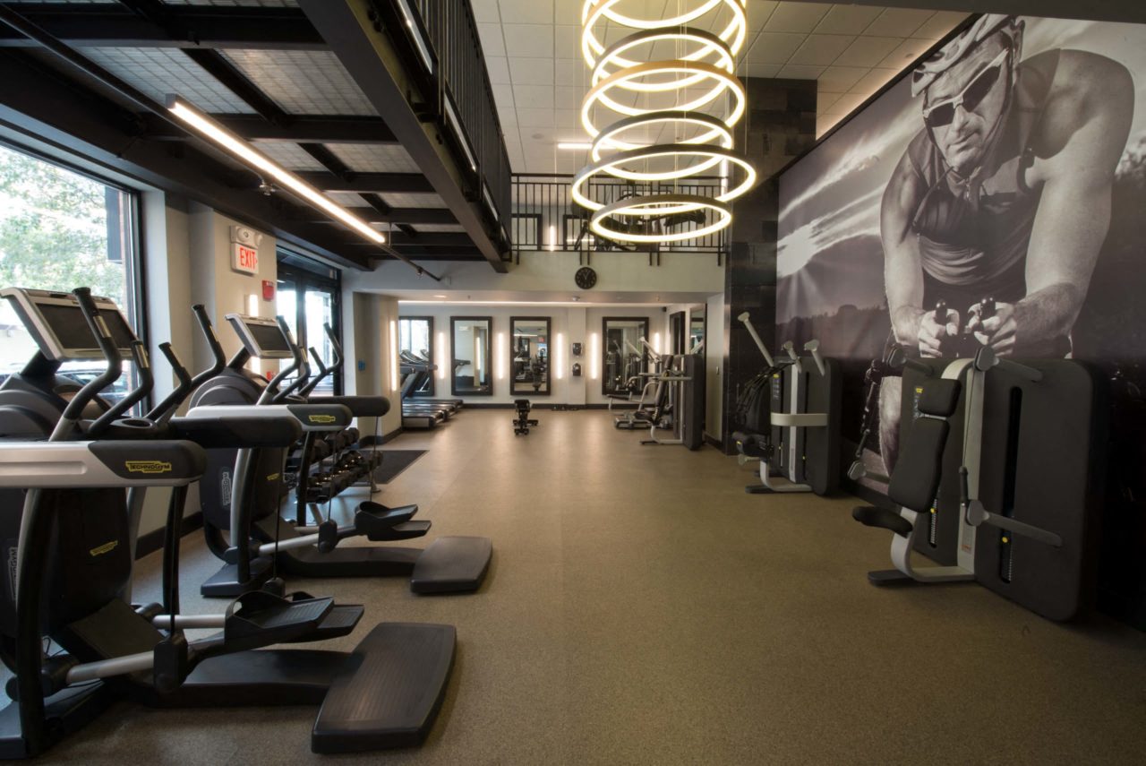 the gym has cardio equipment and a large wall mural of a man working out on