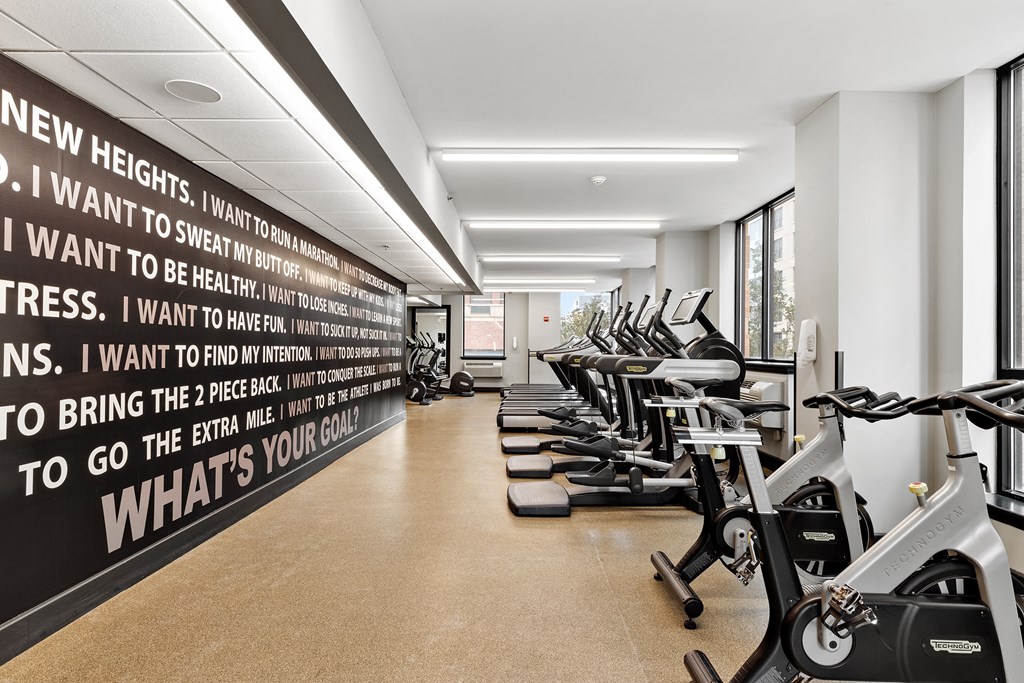a row of exercise bikes in a gym with a wall with a quote