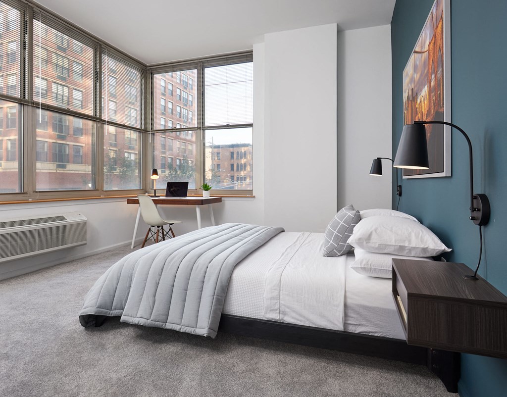 a bedroom with a bed and a desk with a window