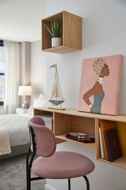 a bedroom with a desk and a chair and a painting of a woman