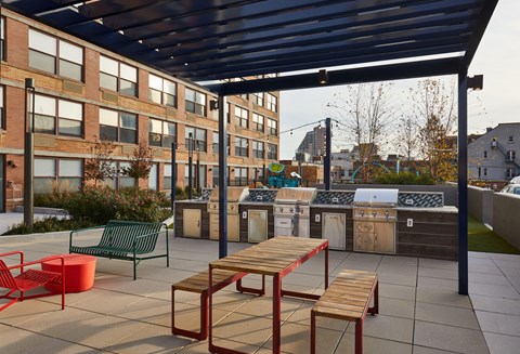 a patio with a picnic table and chairs and a barbecue grill