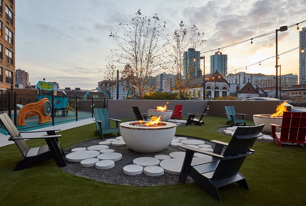 a patio with a fire pit and chairs on a rooftop