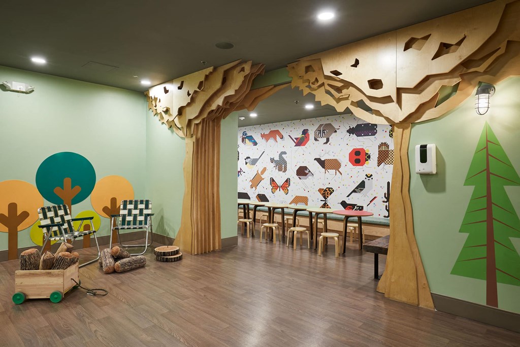 a room with a tree mural and tables and chairs