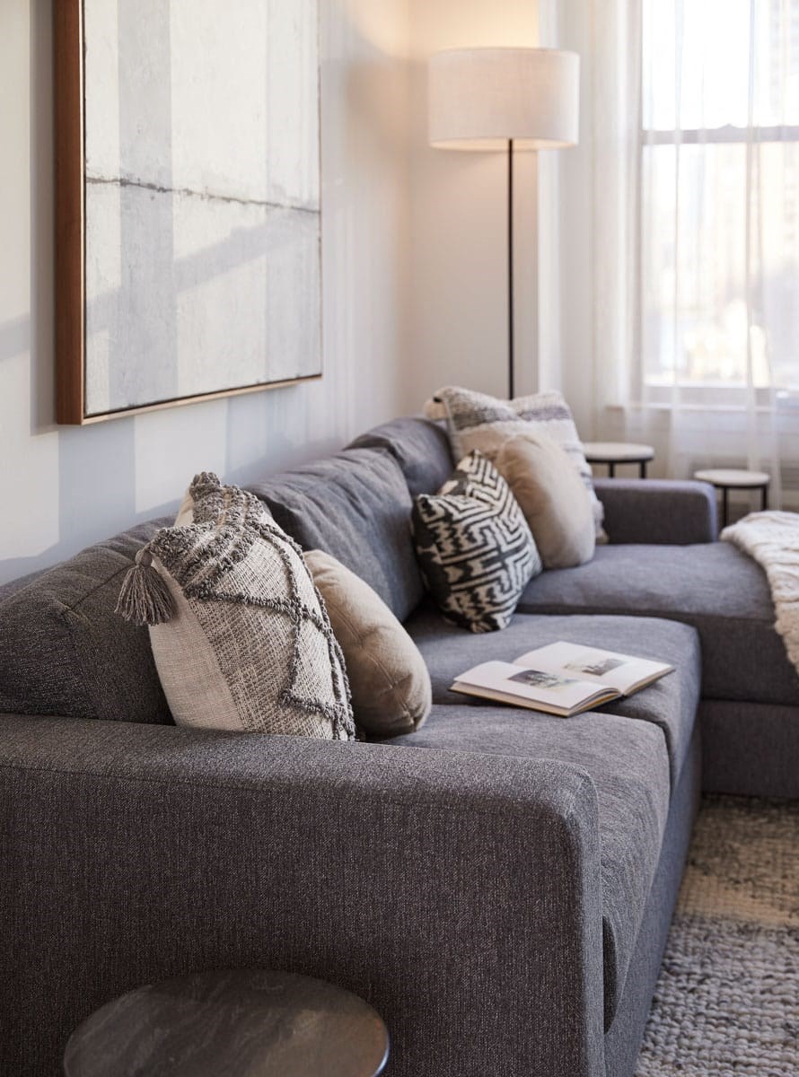 a living room with a gray couch and pillows on it