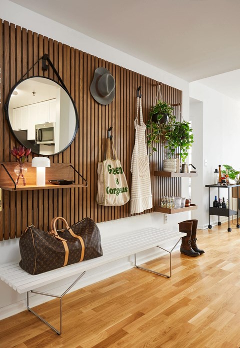 a living room with a bench and a mirror on the wall